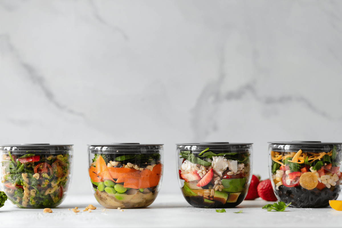 Four clear meal-prep containers with fitted lids arranged on a kitchen counter